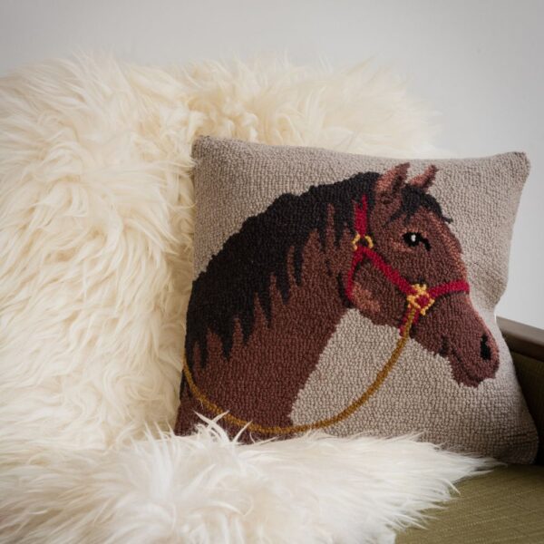 cream textured cushion with brown horse head on a sofa with a sheepskin blanket