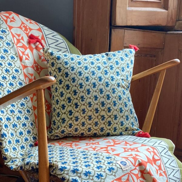 wooden chair with green, blue and orange printed throw draped on it with matching tassel cushion