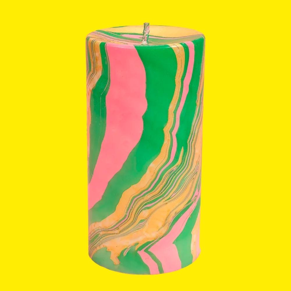 pink green and gold marble effect pillar candle on a yellow background