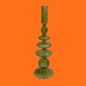 Green decorative ornate candle holder made from glass on an orange background