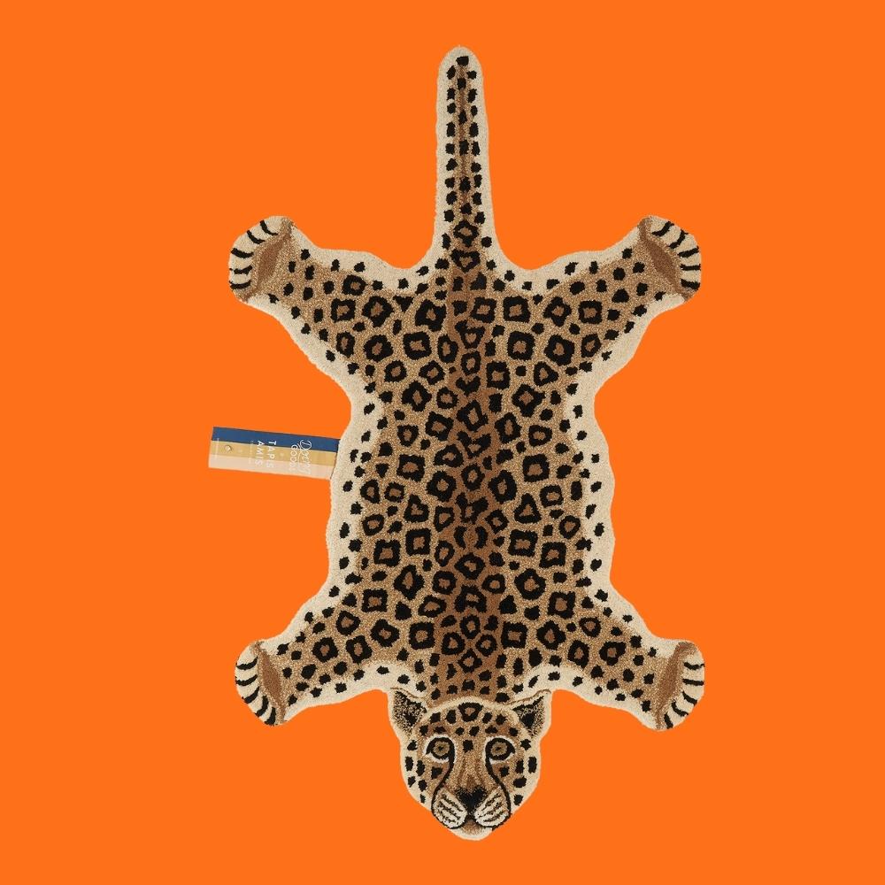 hand tufted leopard shaped animal rug on an orange background