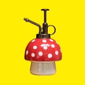 red polka dot mushroom shaped plant mister on a yellow background