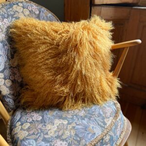fluffy mustard yellow fur sheepskin lambswool cushion on a rocking chair
