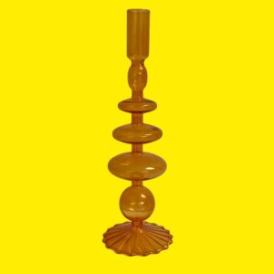 decorative candle holder made from orange glass on a yellow background