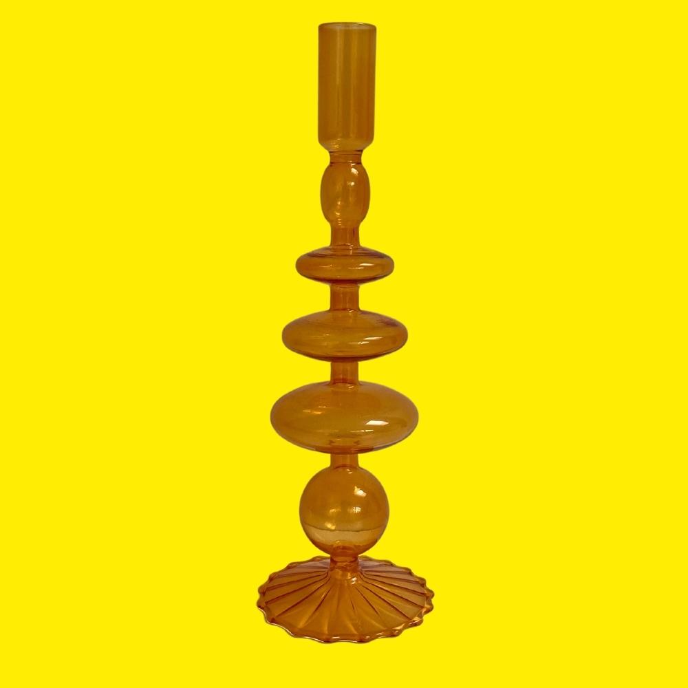 decorative candle holder made from orange glass on a yellow background