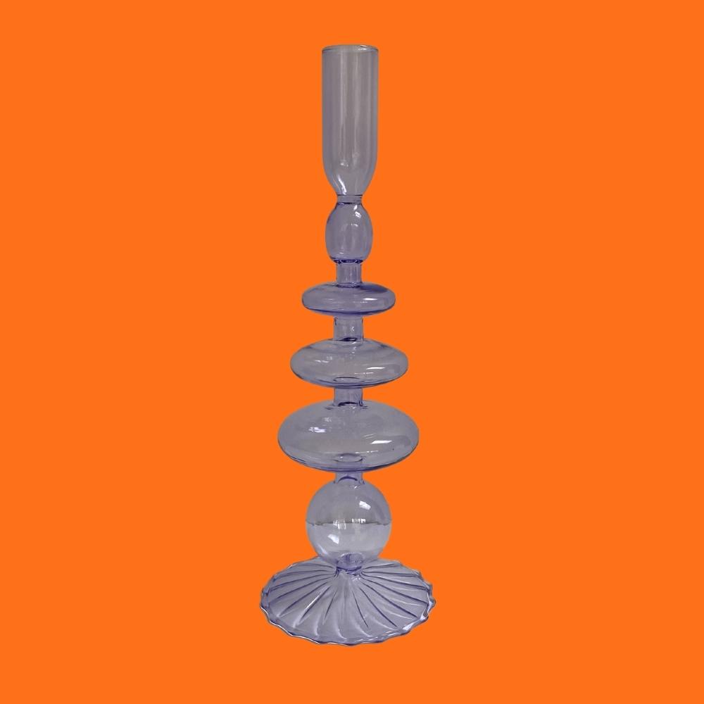 Lilac purple decorative glass candlestick holder on an orange background