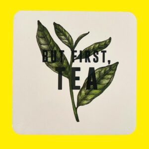 white coaster with a tea leaf print and black text that says but first tea