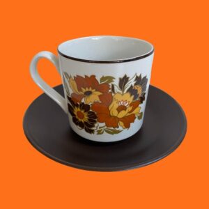 retro 70s cabana floral tea cup with orange and yellow floral print with a brown saucer