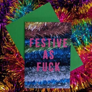 Christmas card with multi coloured tinsel graphic and text that says Festive as Fuck with a green envelope on a tinsel background