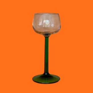 A mid century modern preloved green stem wine glass on an orange background